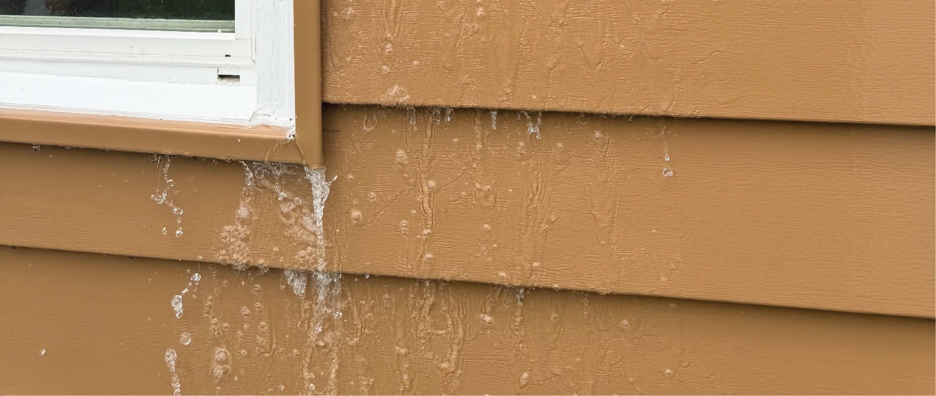 water running down the exterior of a home with brown siding and a white window